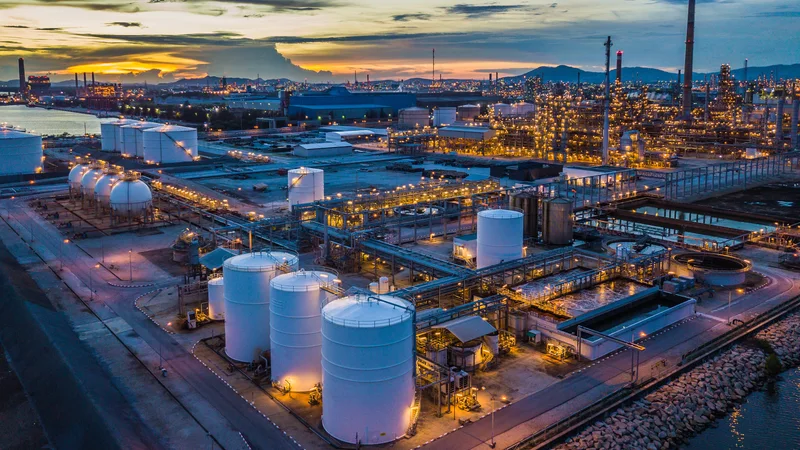 A refinery and tank farm lit up at dusk, seen from the air