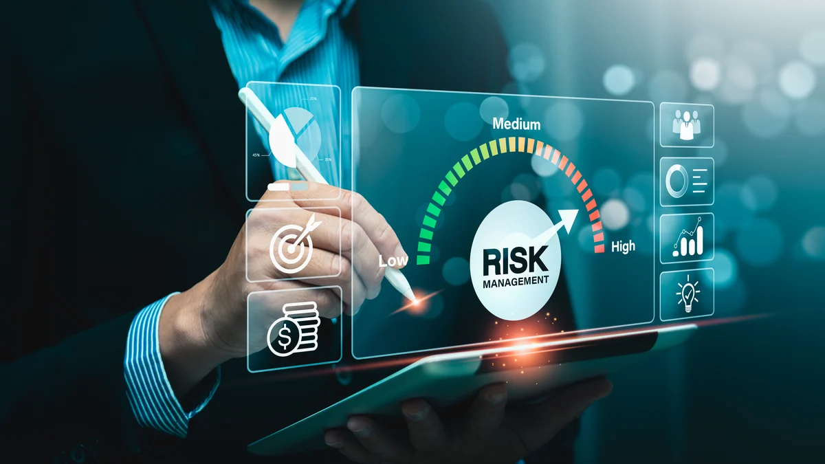 A consultant in a striped shirt draws on a tablet with a stylus beneath a translucent risk management gauge running from low through medium to high, flanked by icons for targets, budget, people, and reporting.